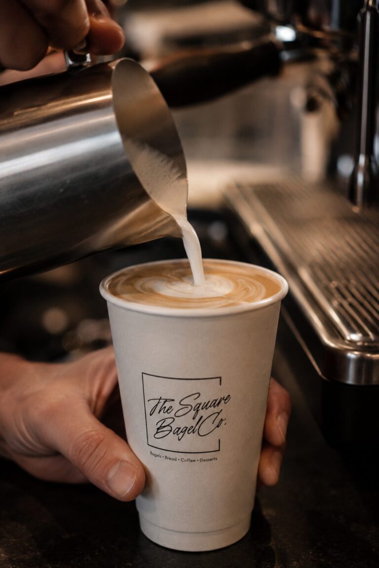 A latte poured into a Square Bagel Co. cup
